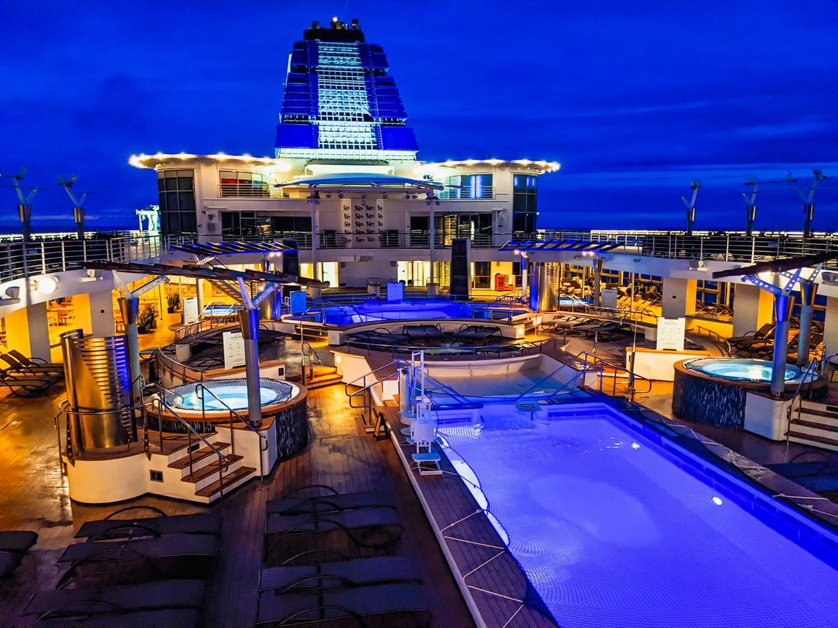 Deck superior com piscinas iluminadas ao anoitecer