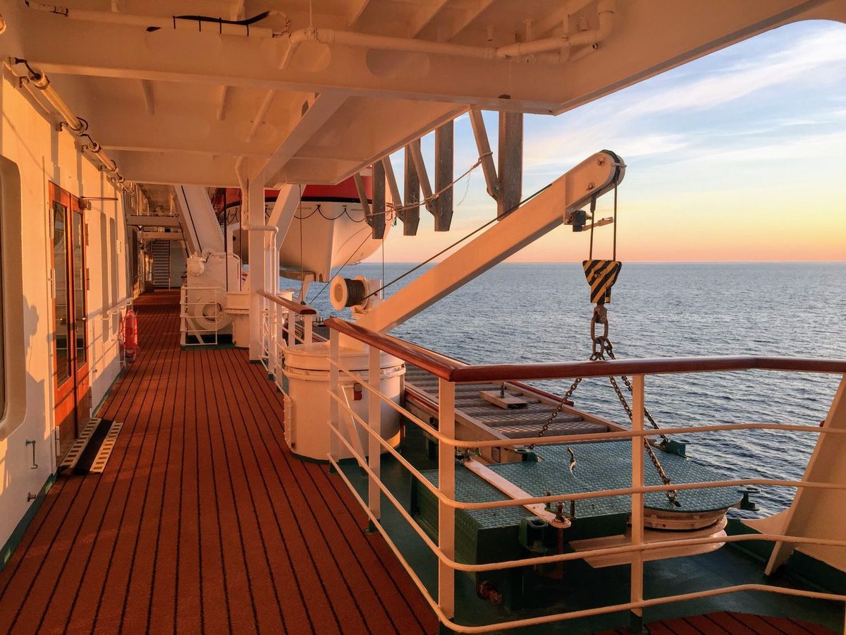 Deck de passeio de um navio ao pôr do sol, de frente para o mar